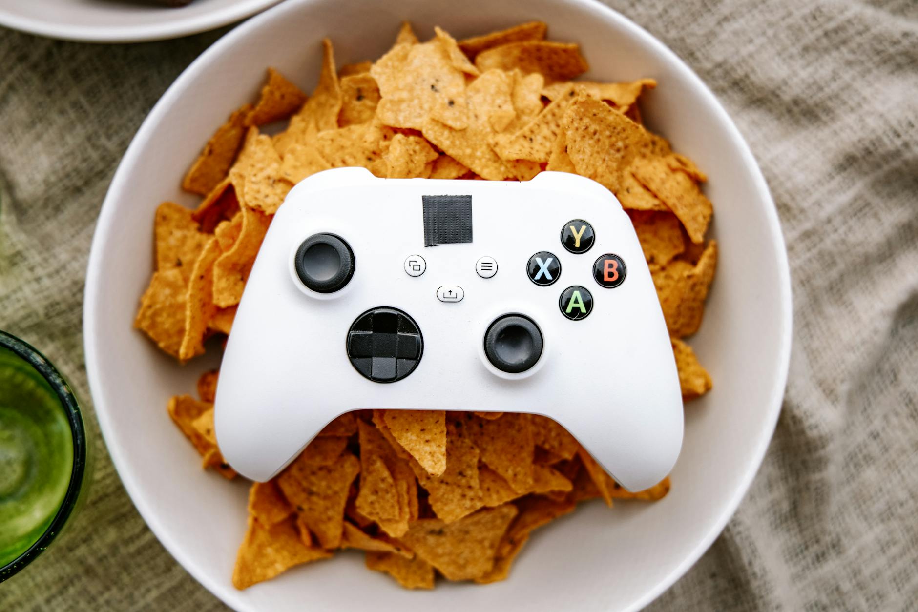 Pad Xbox leżący na misce nachos jako przekąska do grania