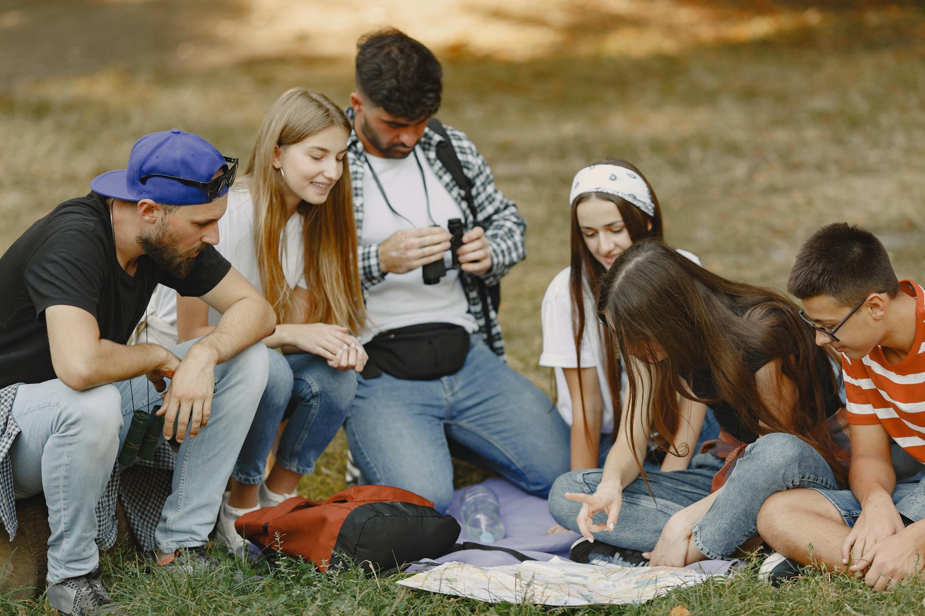 Grupa młodych osób z mapą planuje terenową przygodę na świeżym powietrzu