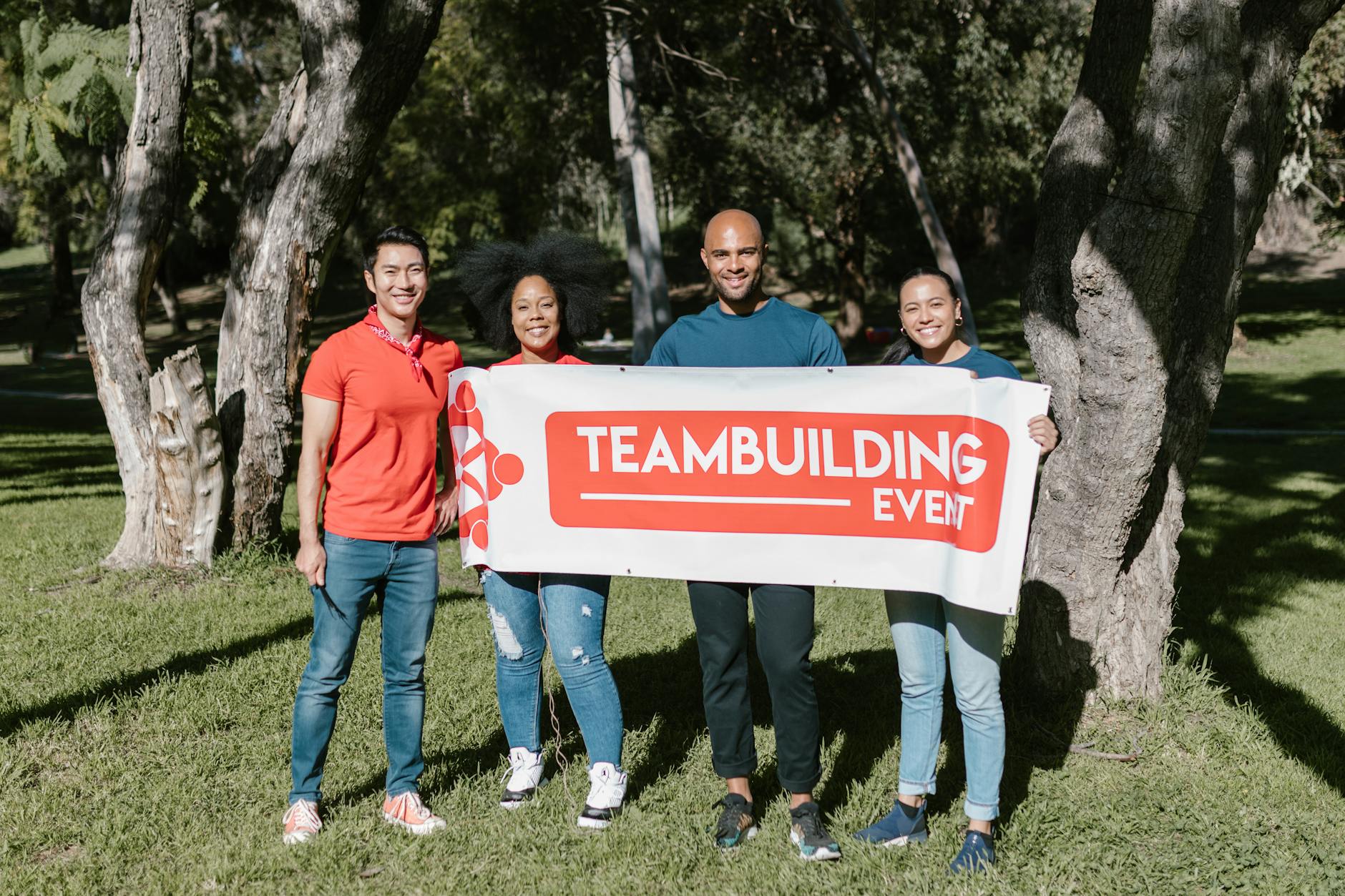 Zespół czterech osób trzymający baner team building w parku