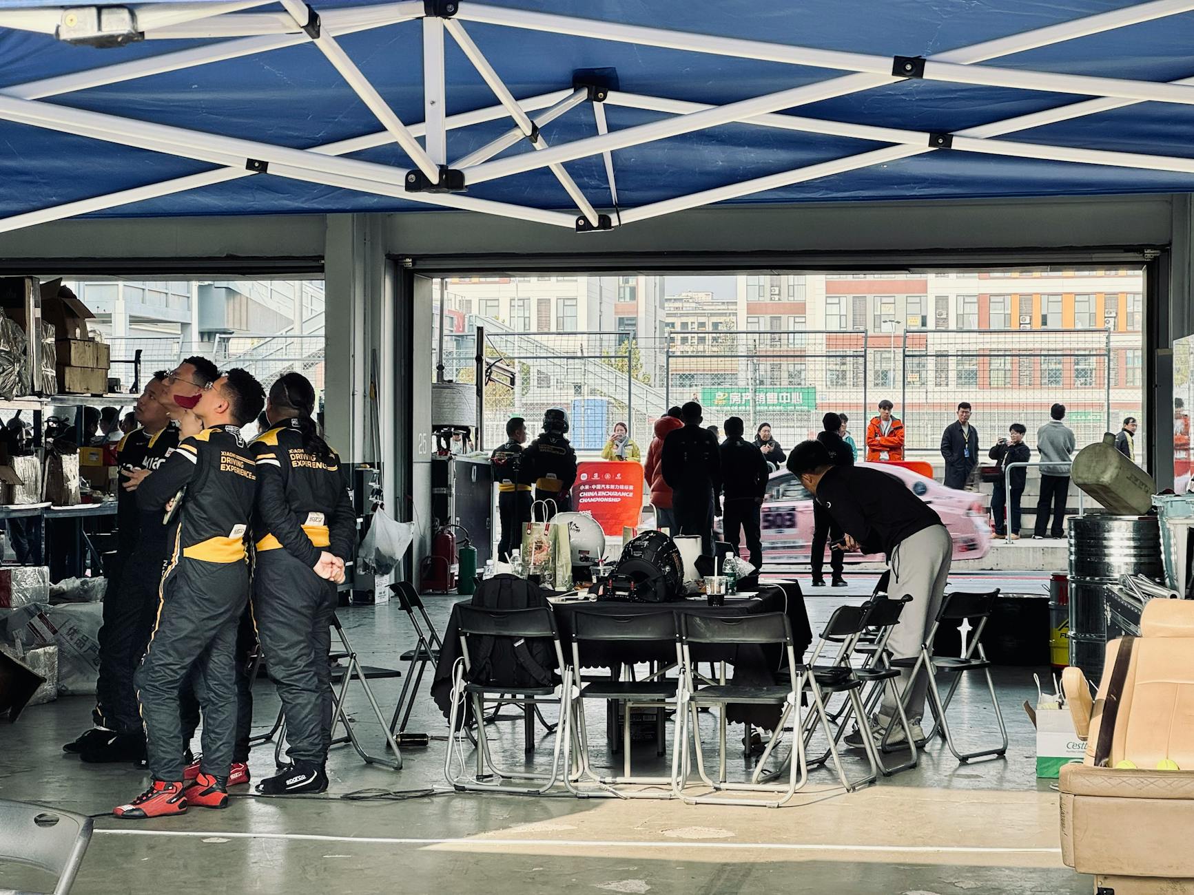 Zespół wyścigowy przygotowuje bolid w boksie, auta mijają garaż