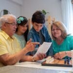 Dziadkowie uczą wnuki grać w szachy w przytulnym domu